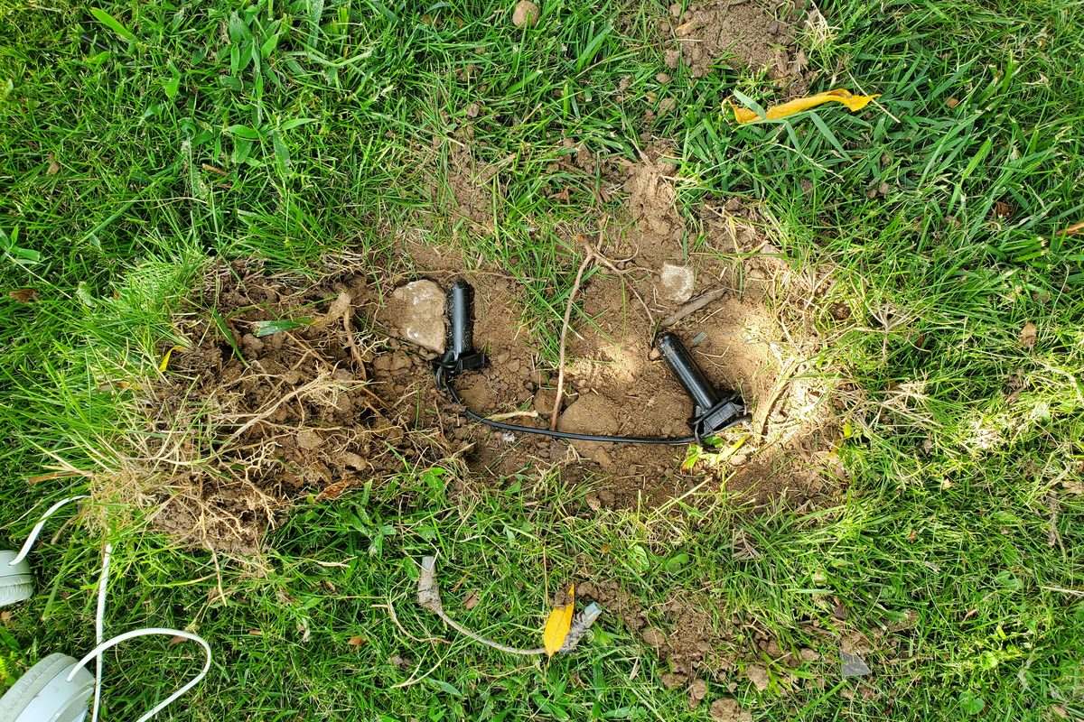 Two waterproof splice connectors joining repaired boundary wire in an opened section of lawn